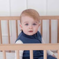 Toddler wearing a dreamy days navy dream sack in cot with white background