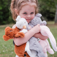Child holding multiple Dreamy Days animal comforters outdoors