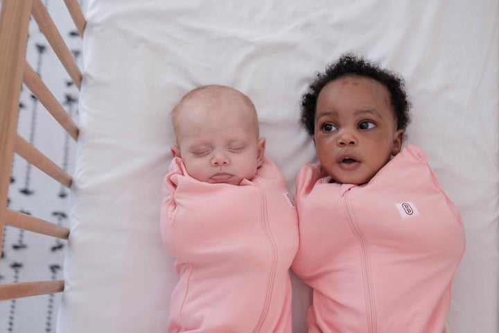 Two babies wearing dreamy days pink dream swaddle
