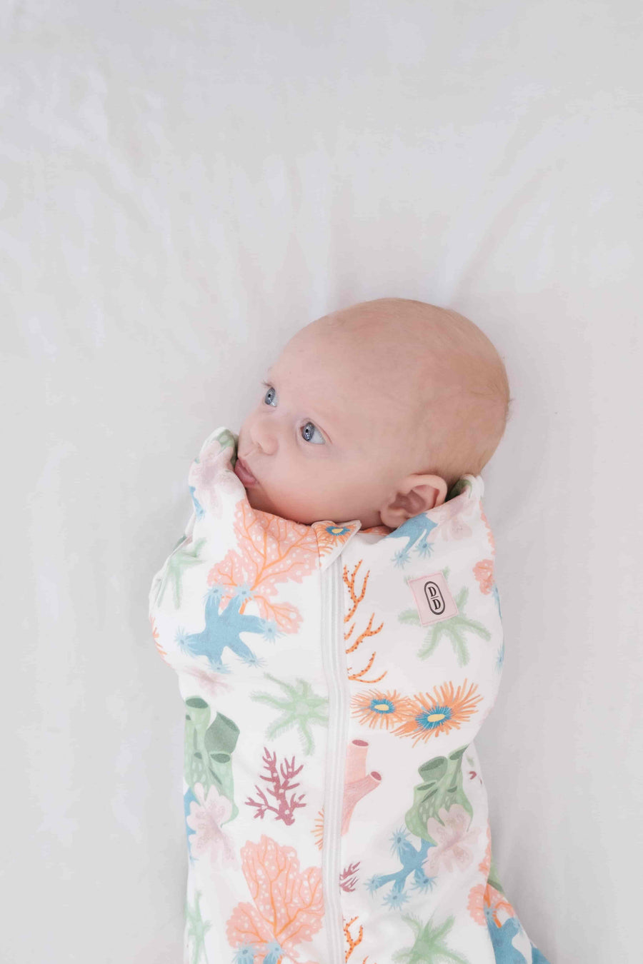 Dreamy days baby dream swaddle pink coral on white surface