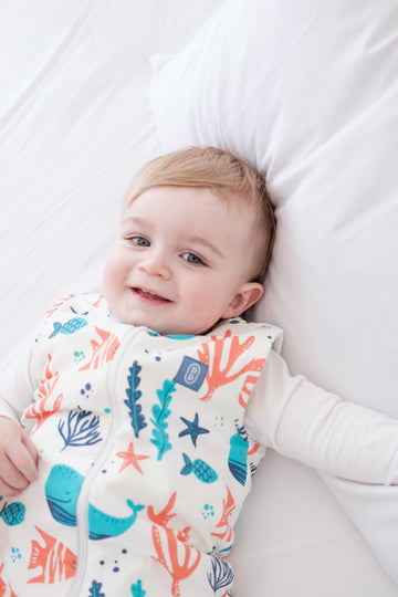Toddler wearing the Dreamy Days ocean themed dream sack on white bed
