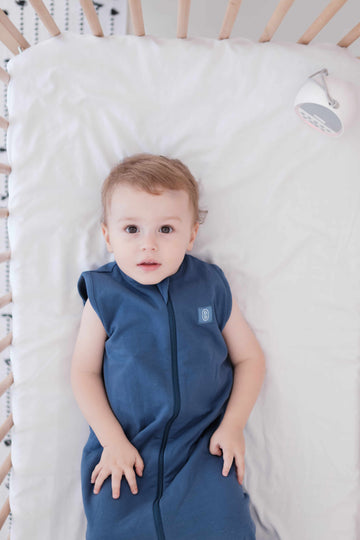 Toddler wearing a dreamy days navy dream sack in cot