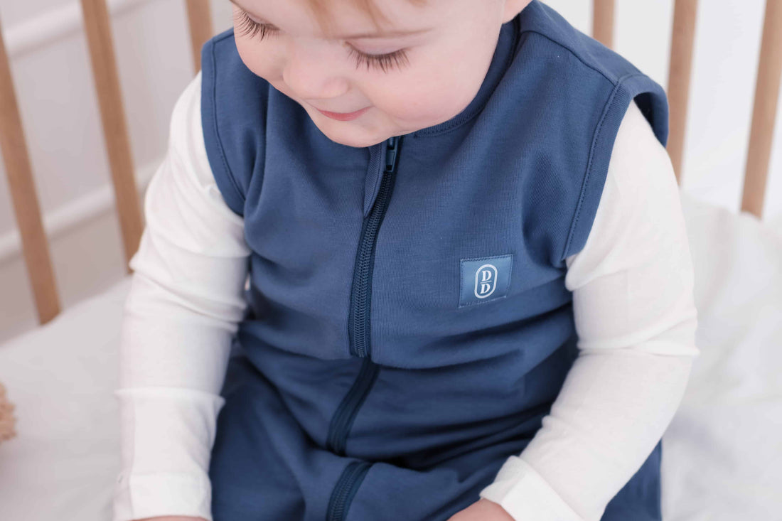 Toddler wearing a dreamy days navy dream sack in cot