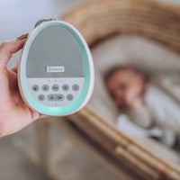 Mother holding Dream Pod baby white noise machine and night light